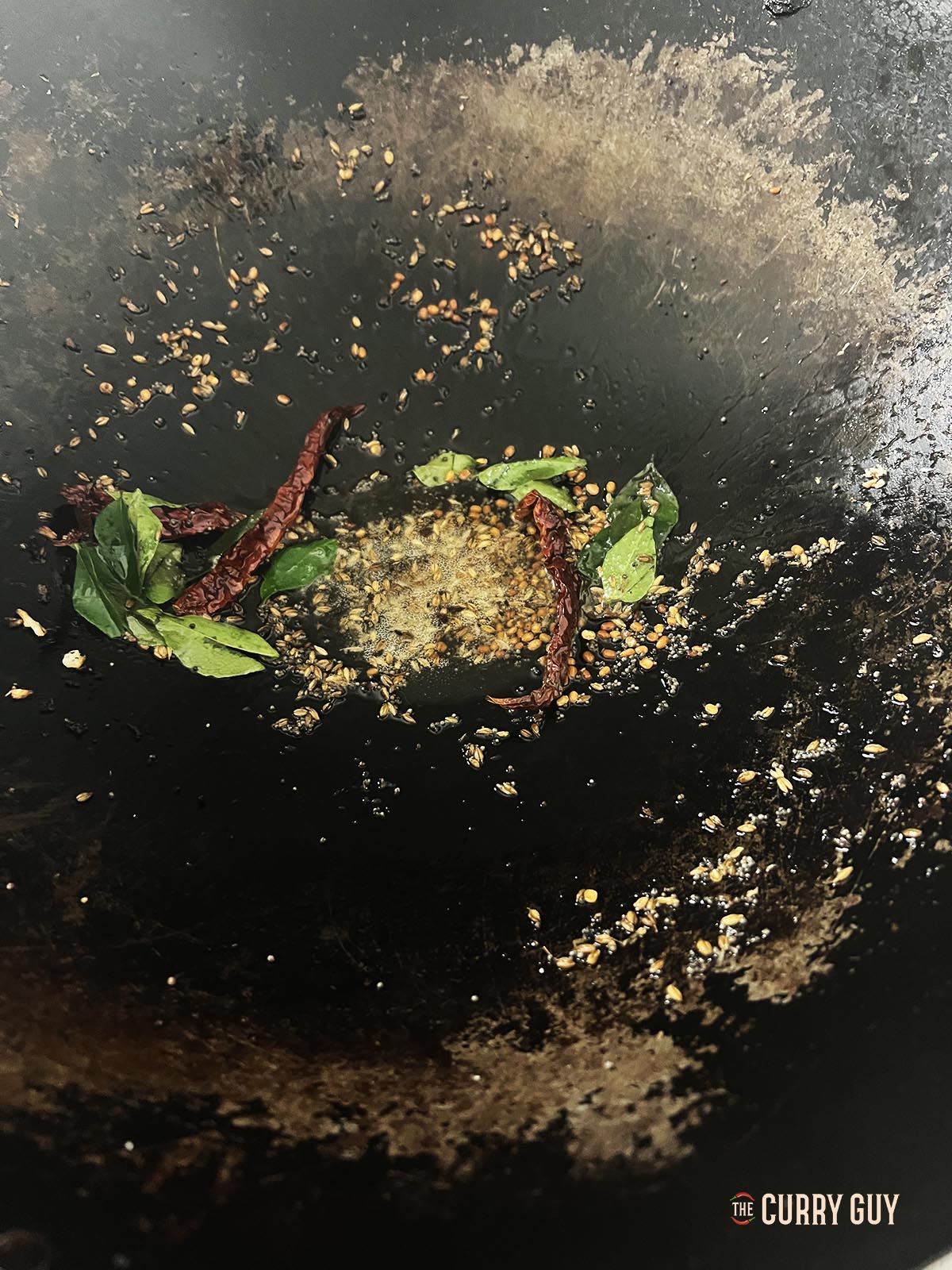 Frying the aromatic ingredients in coconut oil in a wok.