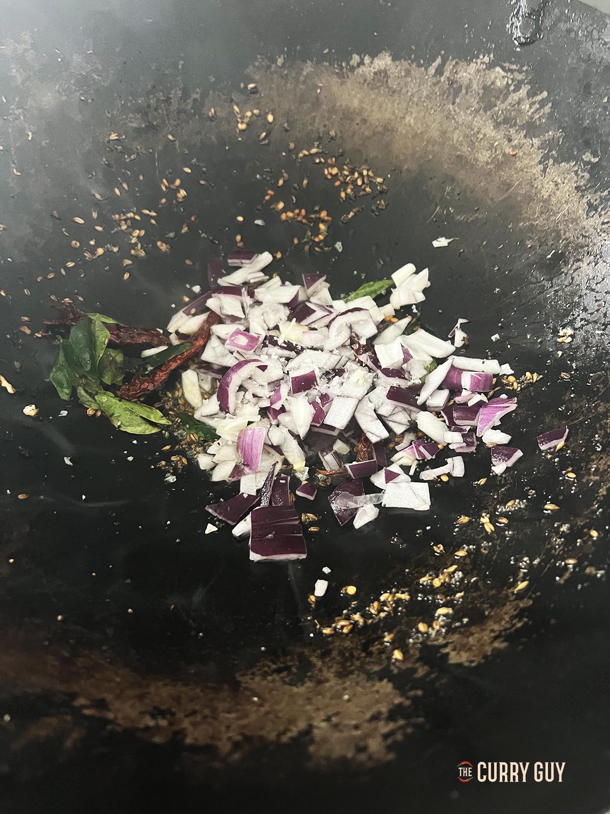 Adding the chopped onions to the wok.