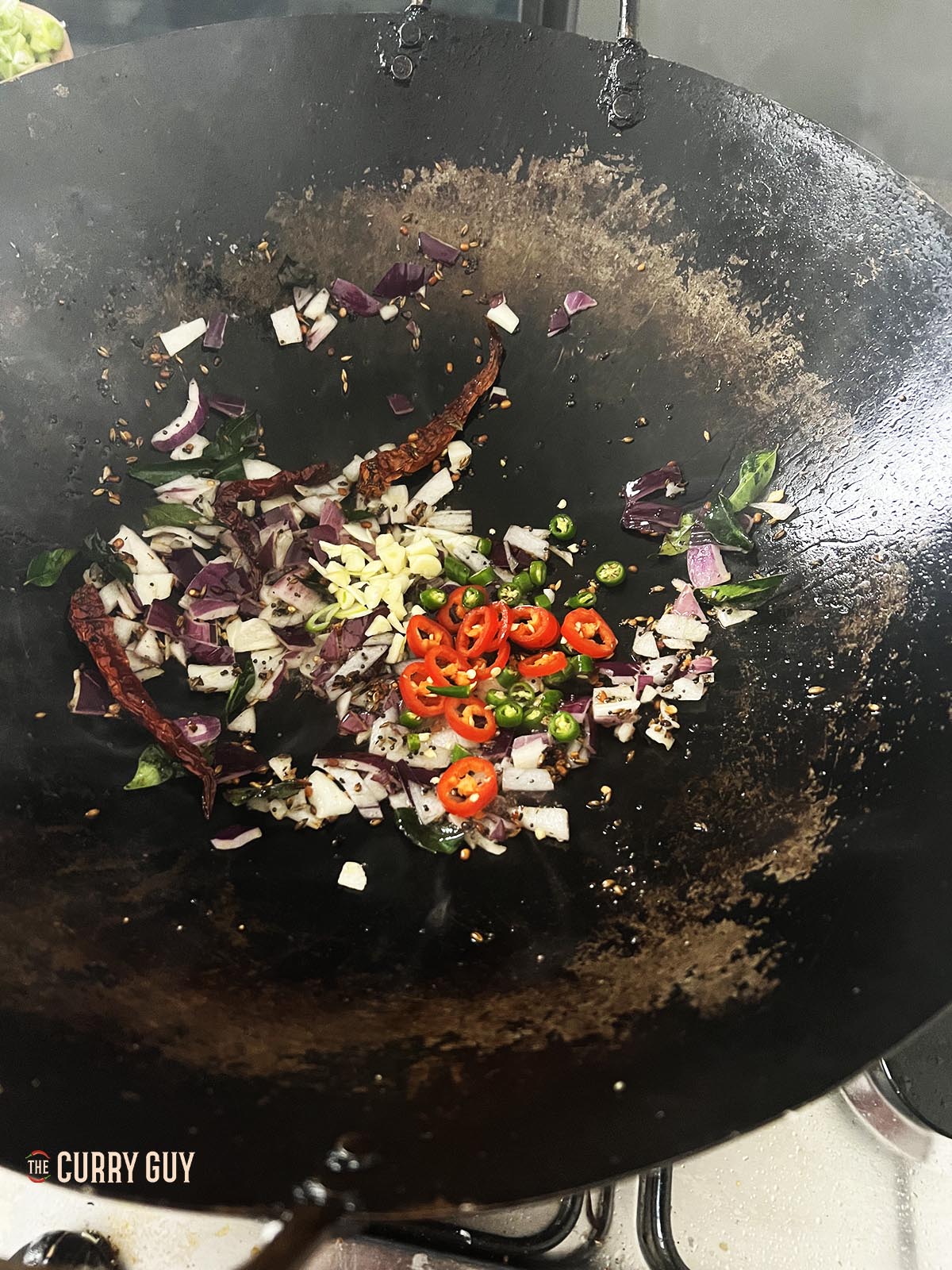 Adding the chillies and garlic to the wok.