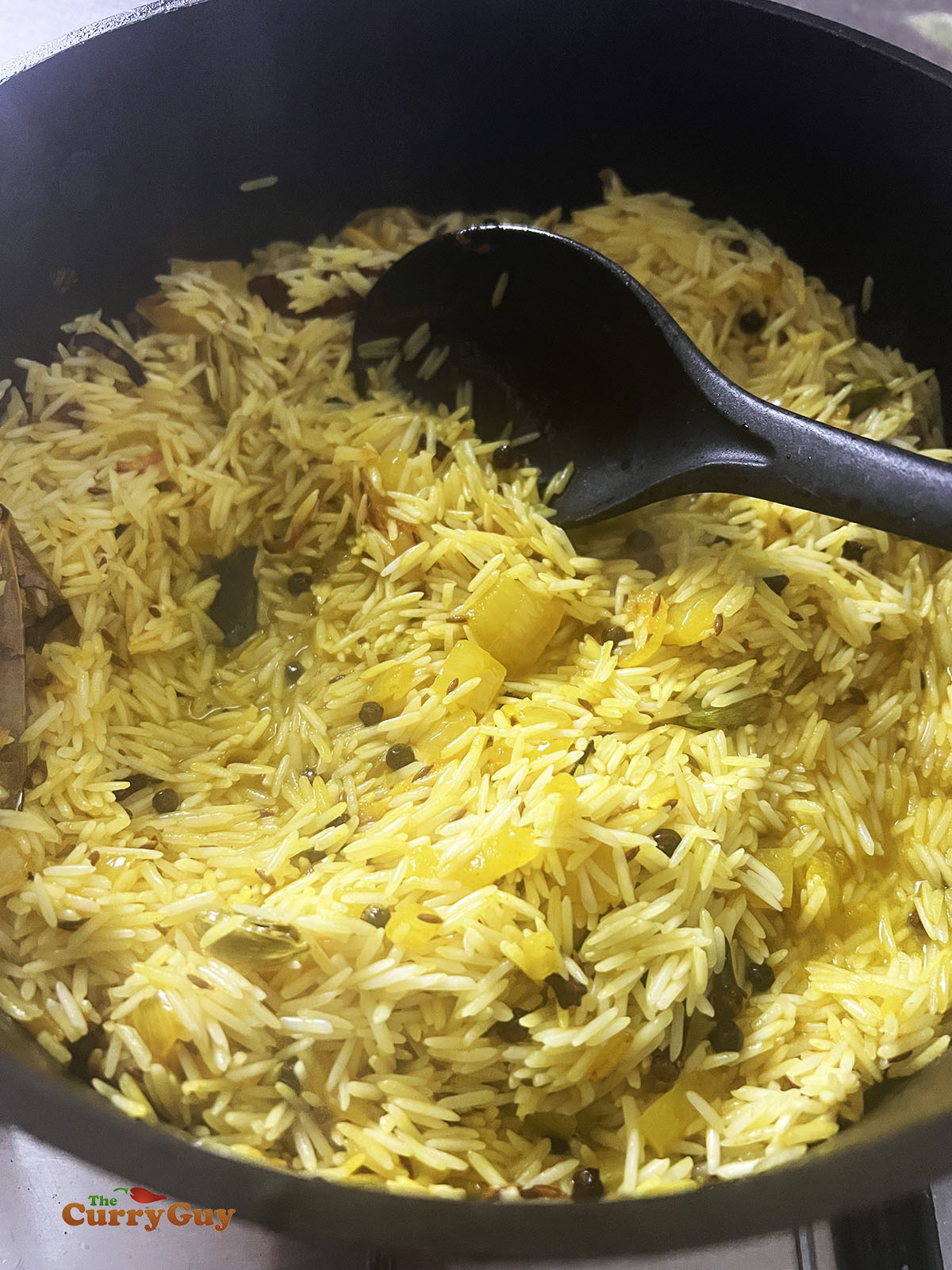 Stirring rice into the ghee and spices.
