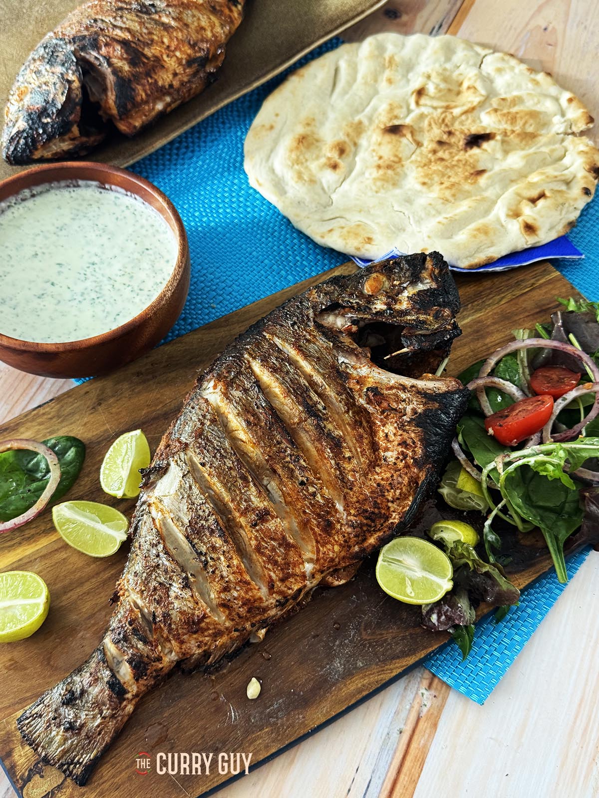 The fish served on a wooden platter with flatbreads and coriander chutney.
