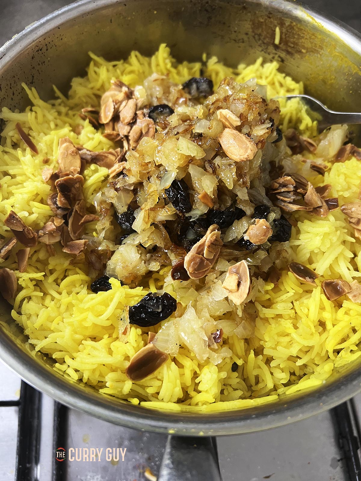 Adding the fried onions and raisins to the rice.