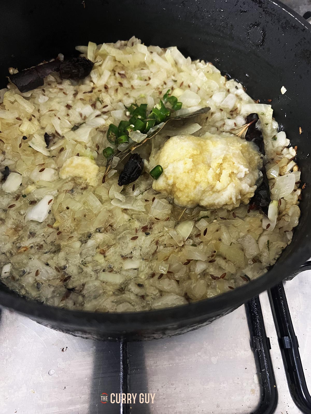 Adding onions, garlic and ginger paste and chillies to the pan.