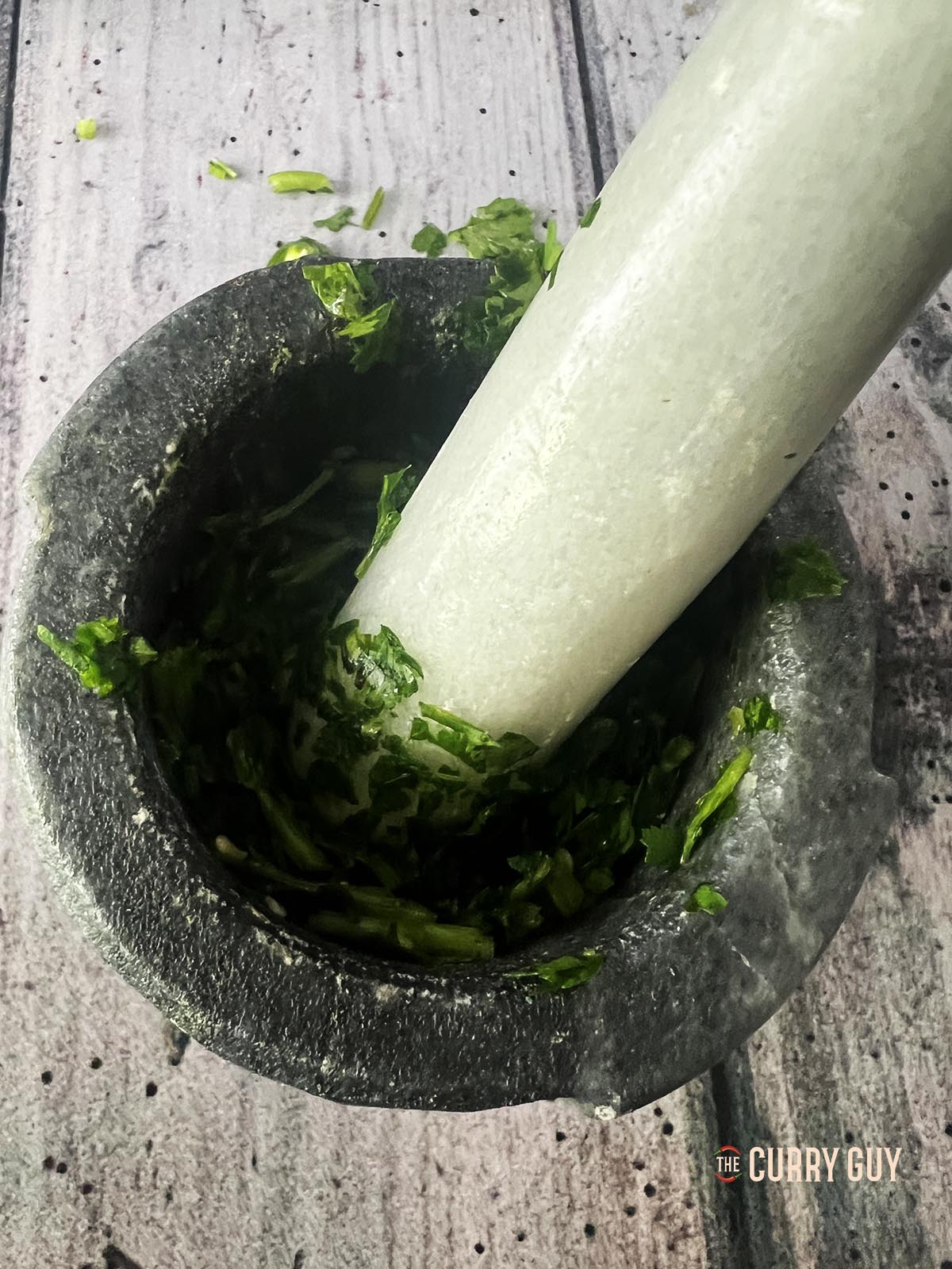 Pounding the chillies and coriander (cilantro) in a pestle and mortar.
