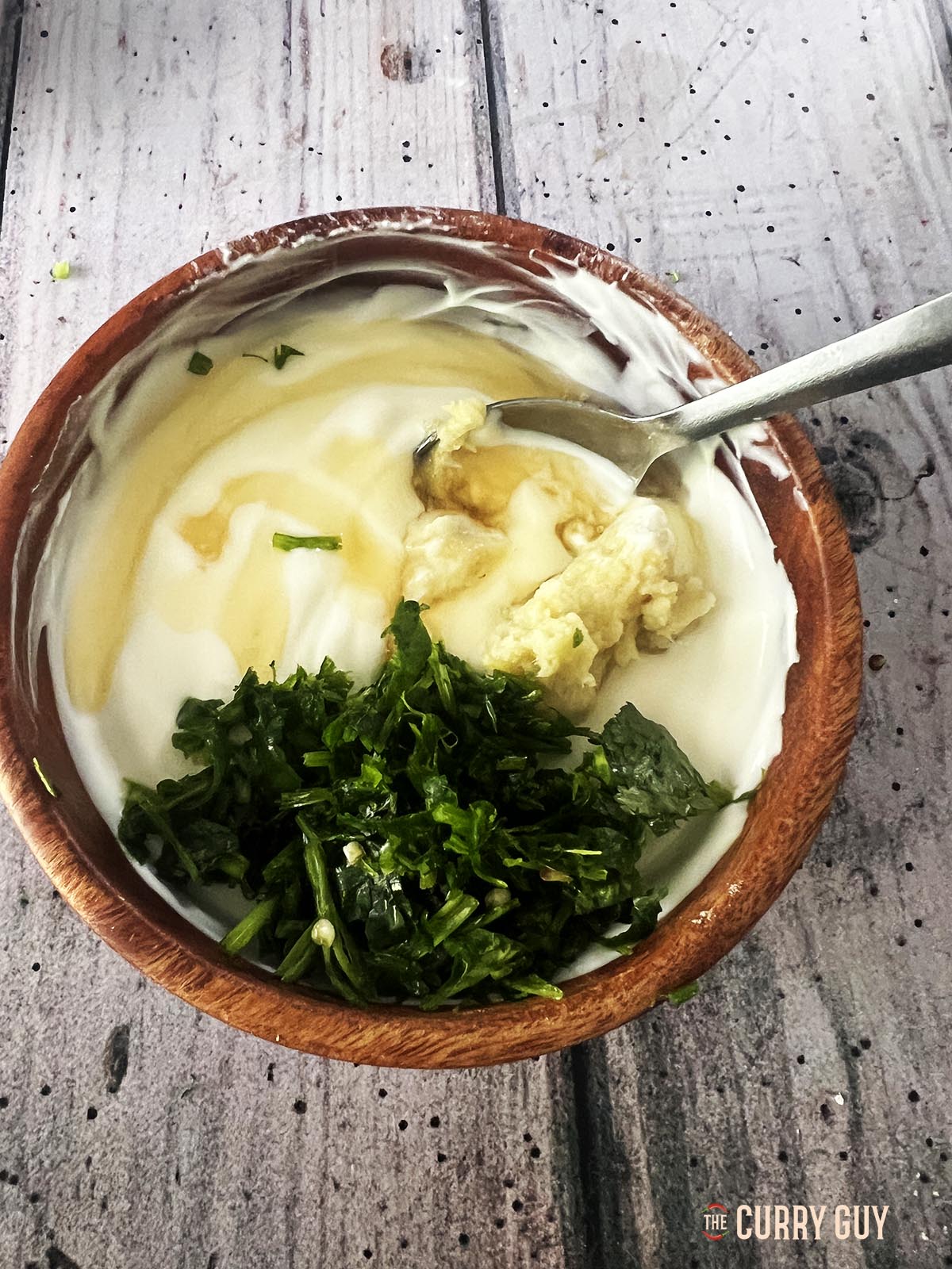 The whisked yoghurt, garlic and ginger paste and the pounded coriander and chillies in a mixing bowl.