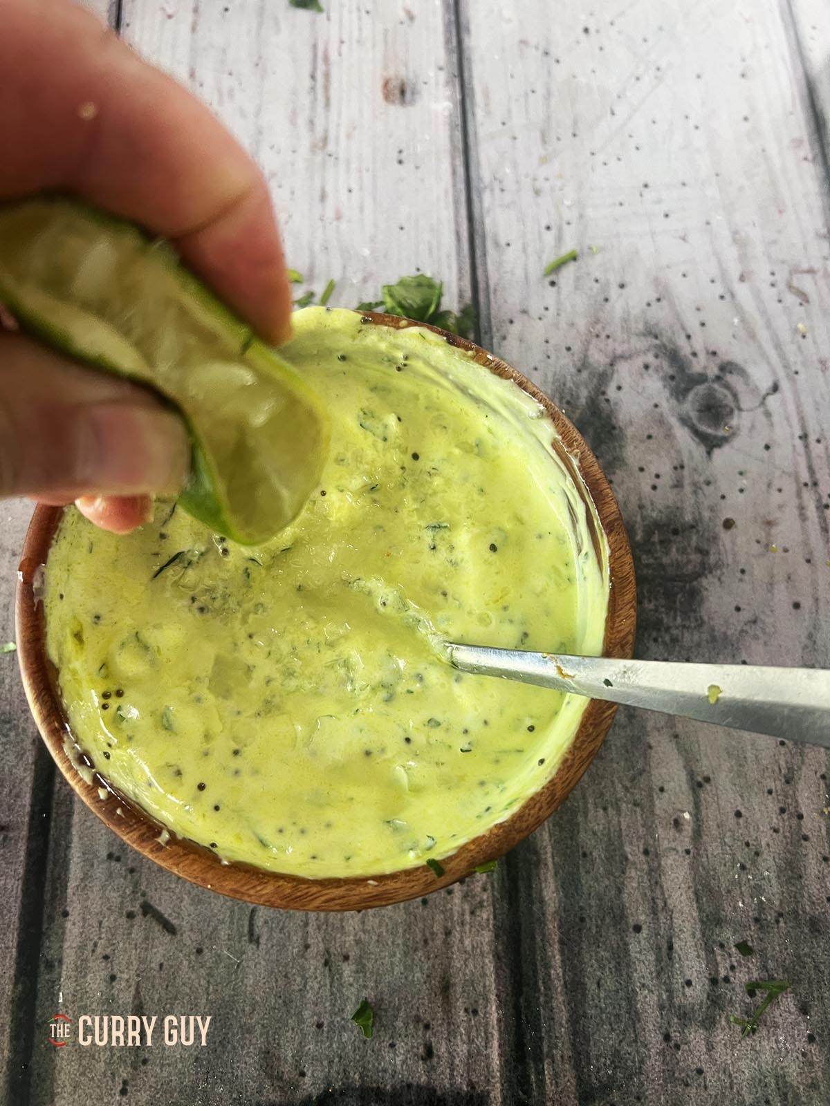Adding lime juice to the raita.