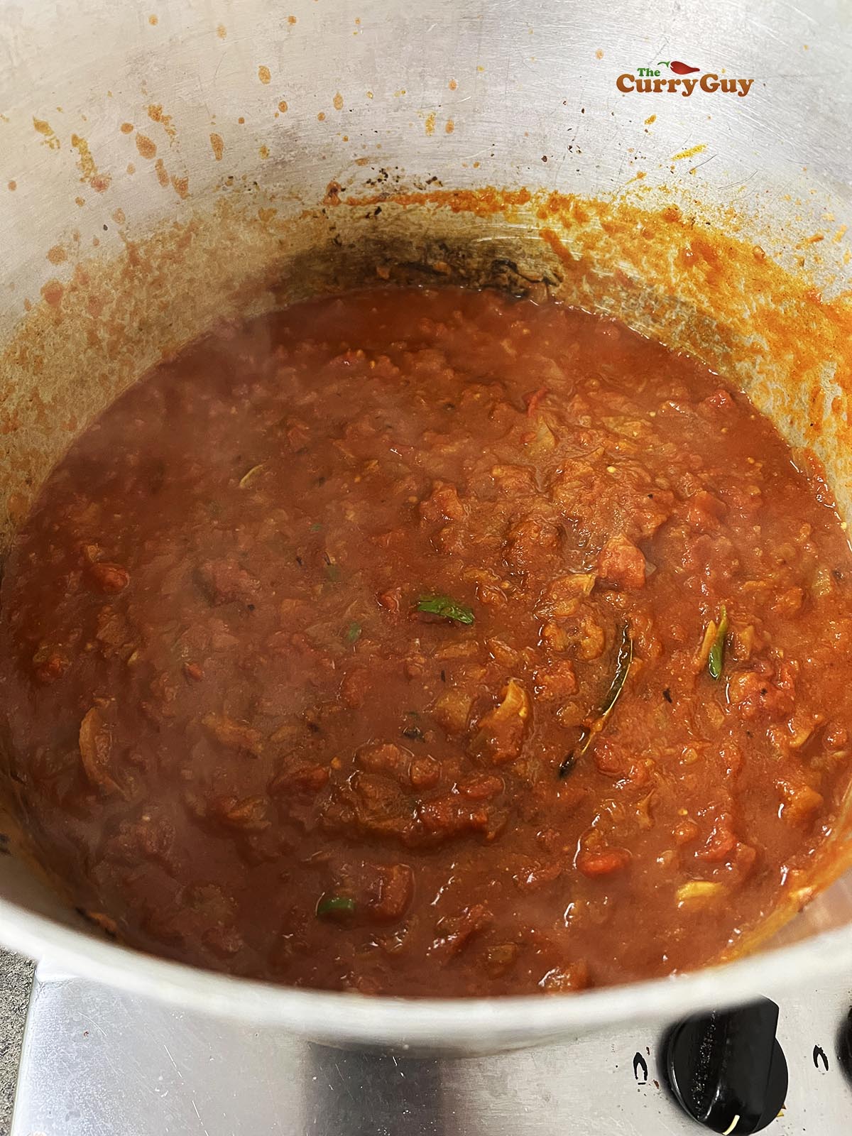 Adding the chopped tomatoes to the pot and bringing to a simmer.