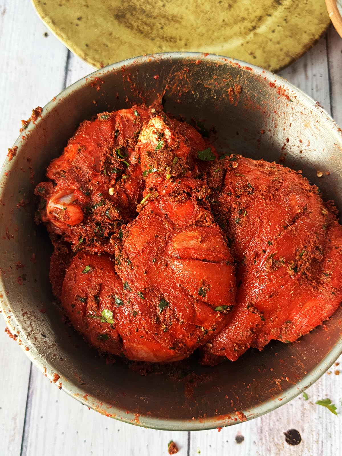 Applying the pastes and dry spices to the chicken.