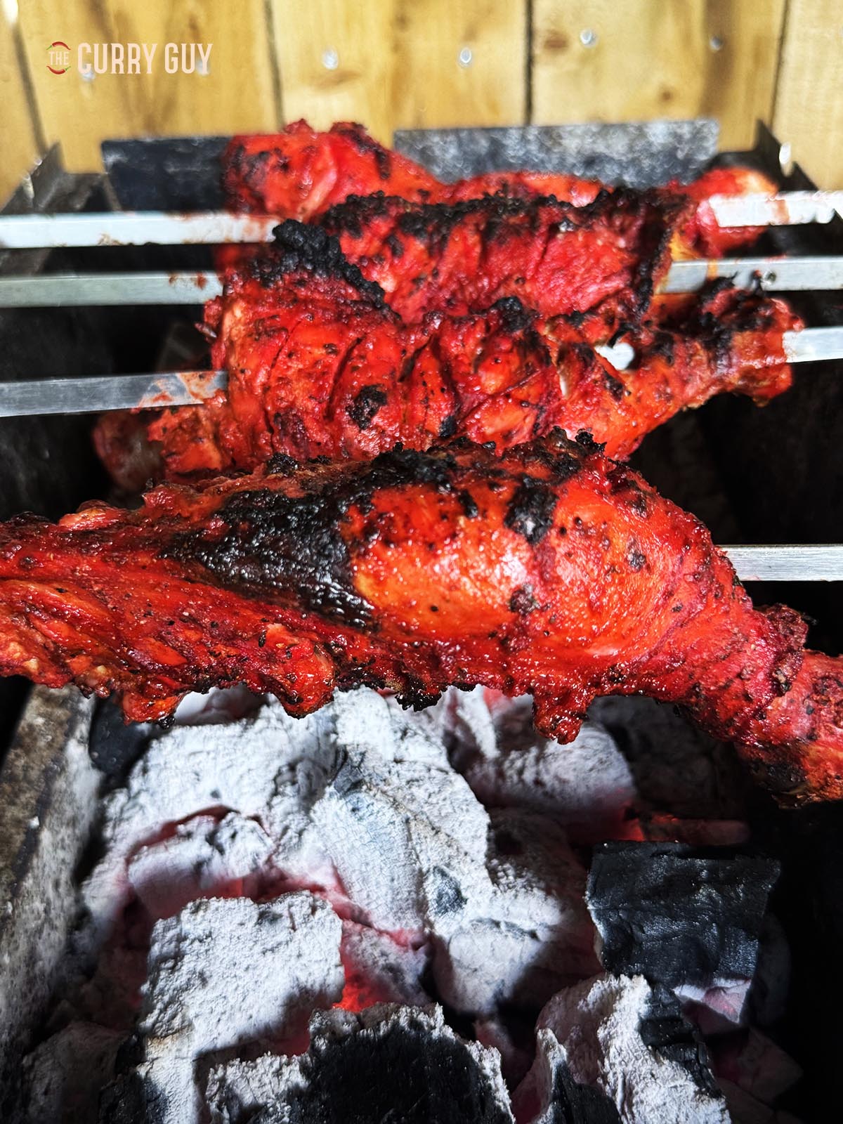 Charring the chicken over the hot coals on the barbecue. 