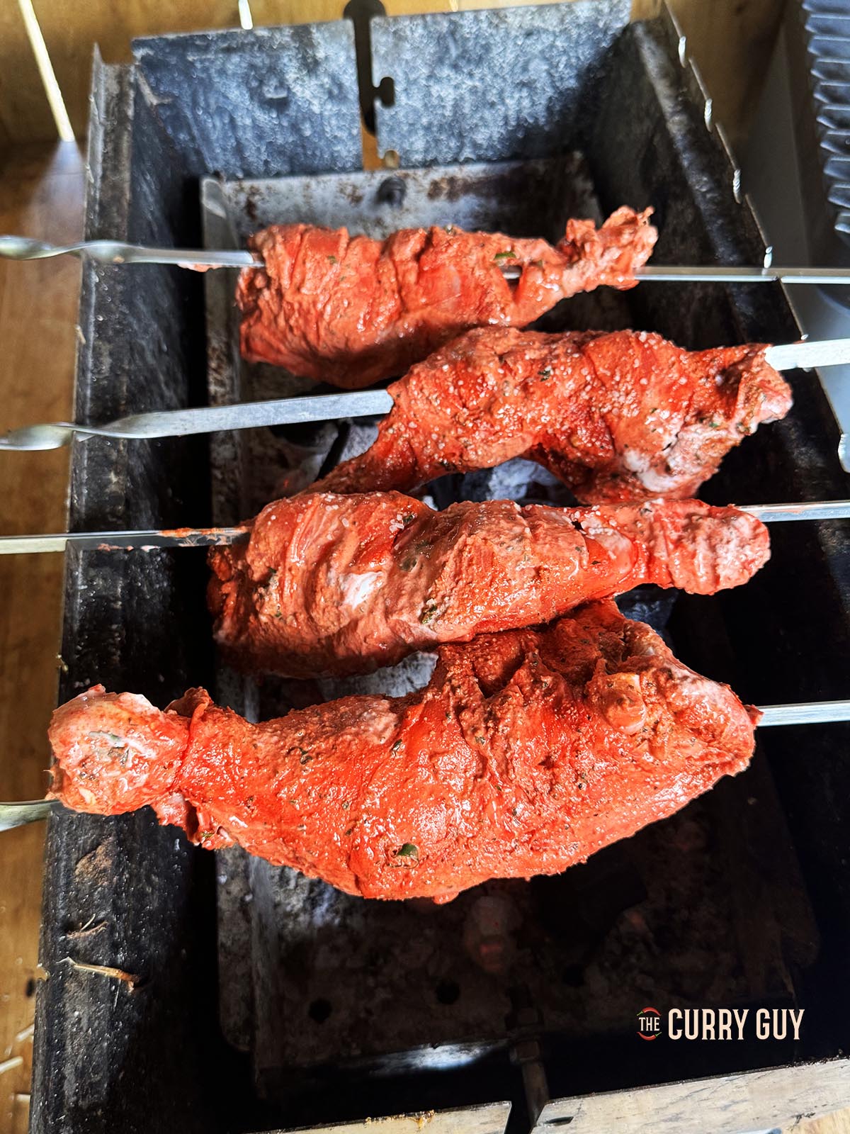 The chicken on skewers cooking over a charcoal fire.