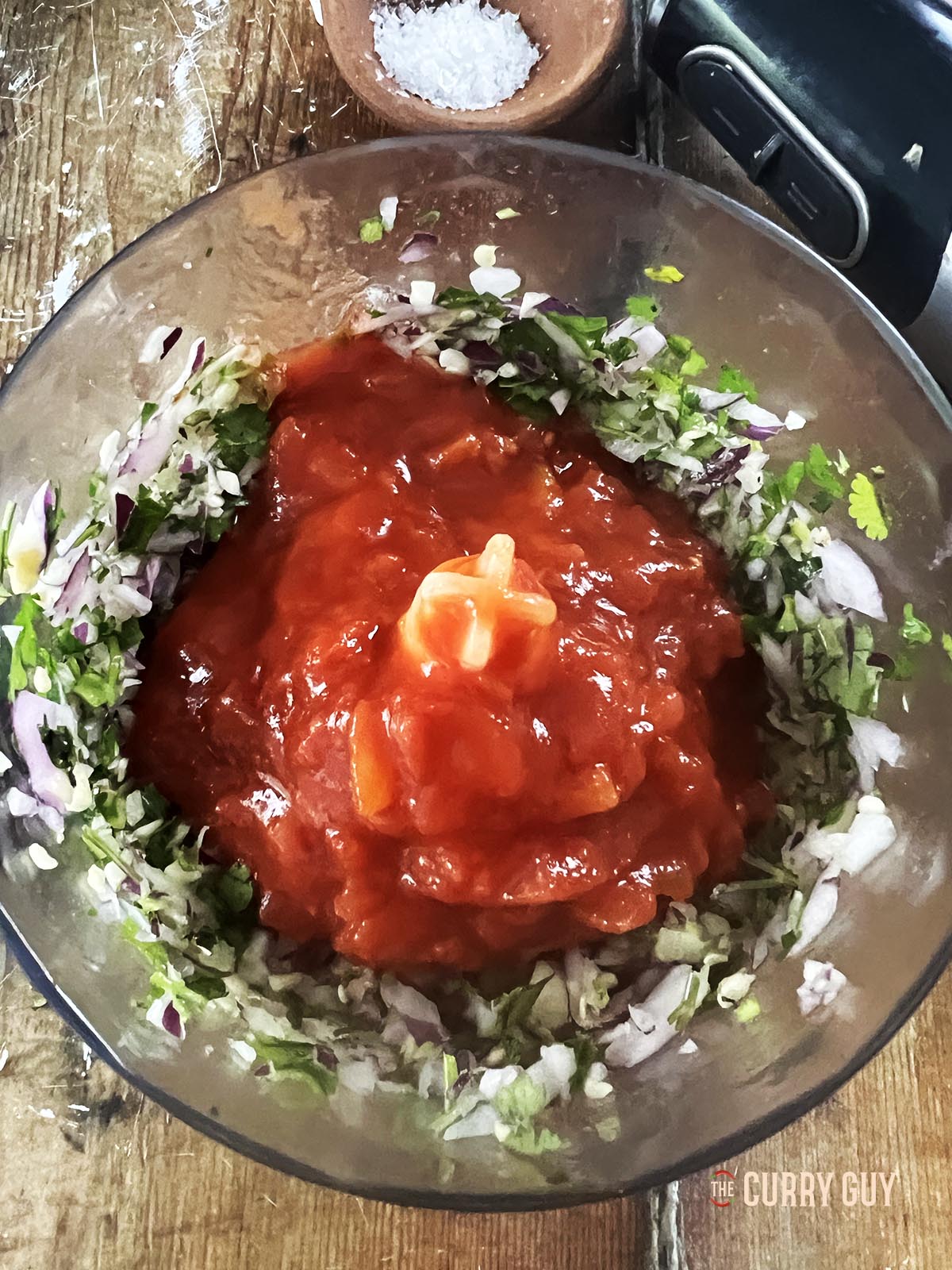 Adding the chopped tomatoes to the finely chopped ingredients.