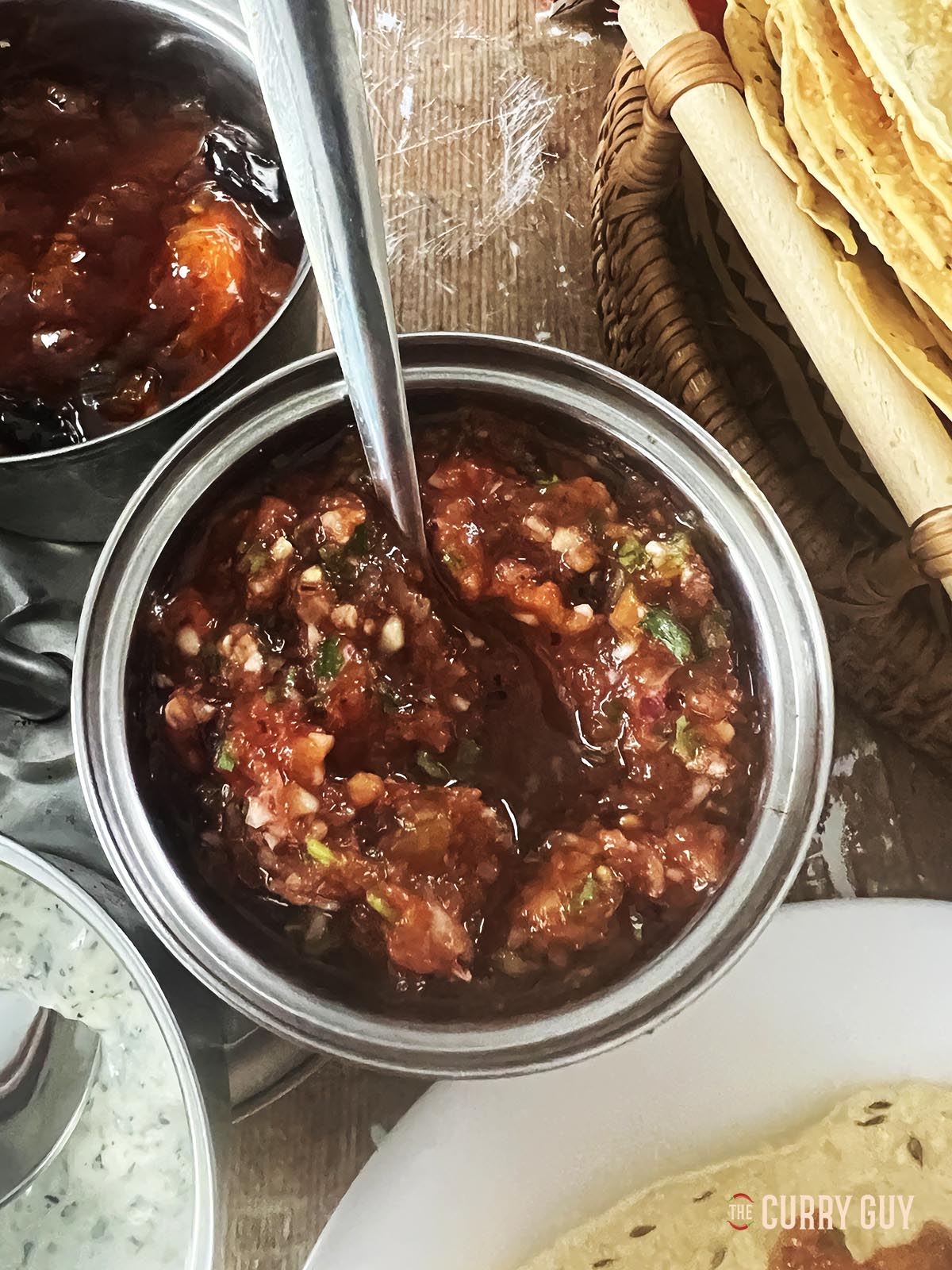 Tomato chilli chutney in a serving bowl with poppadoms.