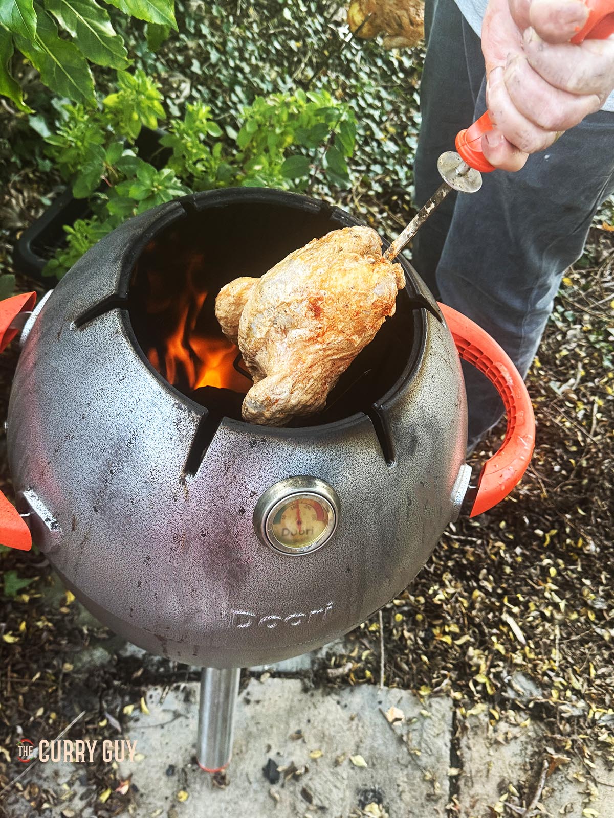 Placing the pheasant skewer in the tandoor oven.
