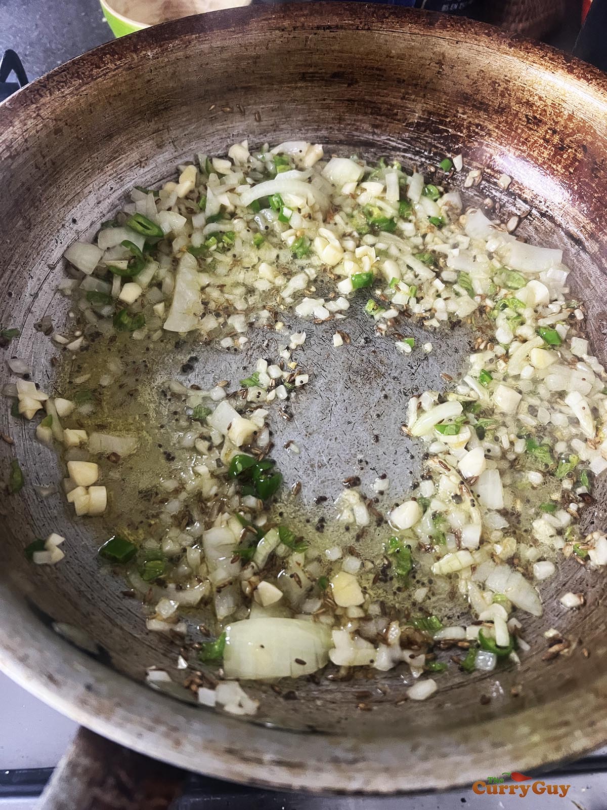 Adding chopped garlic and chilies to the pan to fry for 30 seconds.