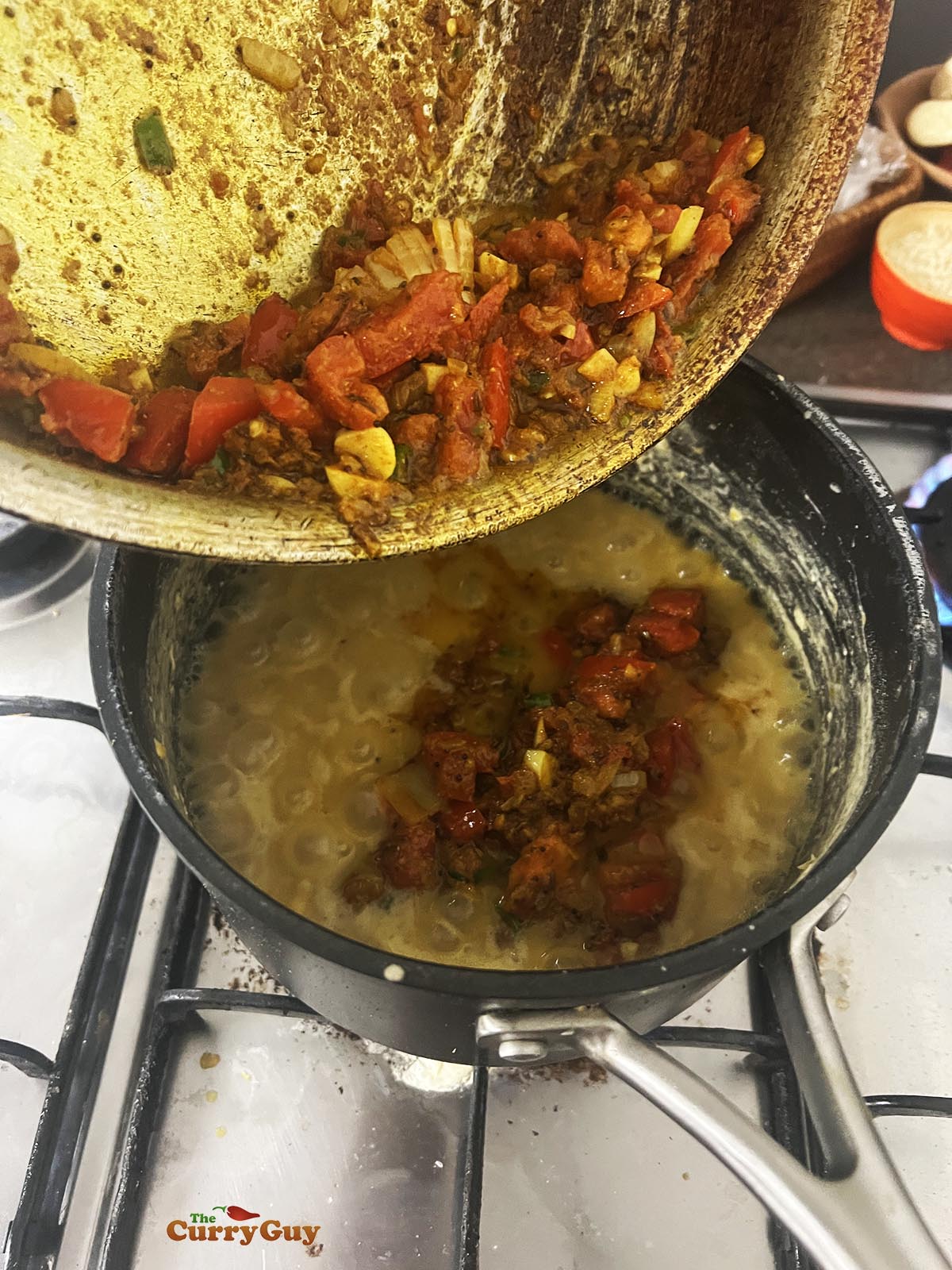 Adding the tarka to the cooked lentils.