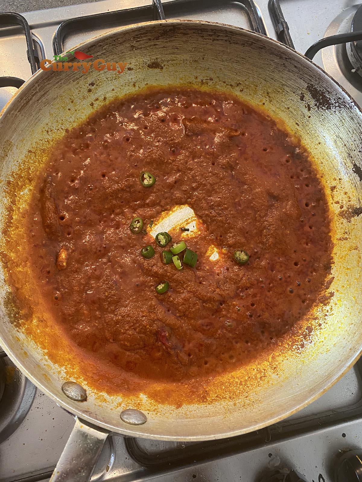 Adding green chillies to the sauce.