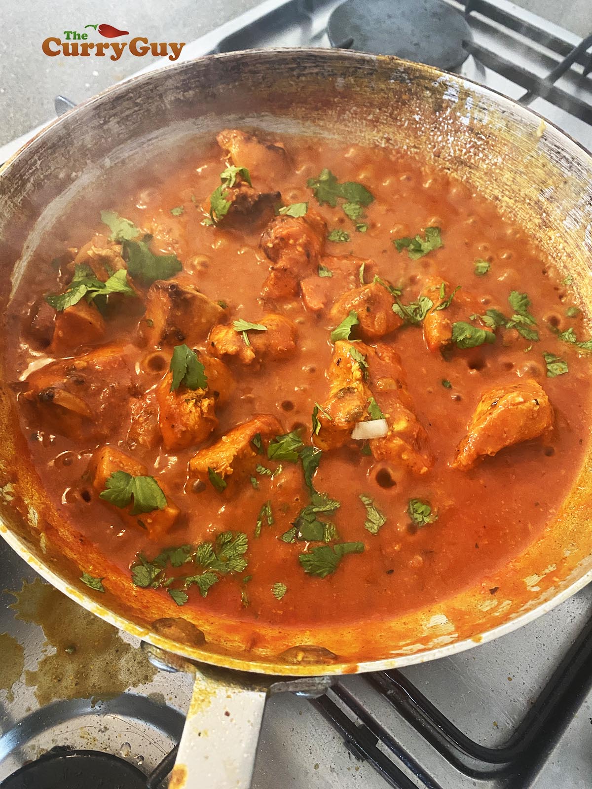 FInishing the curry off by adding food colouring and garnishing with chopped coriander (cilantro)