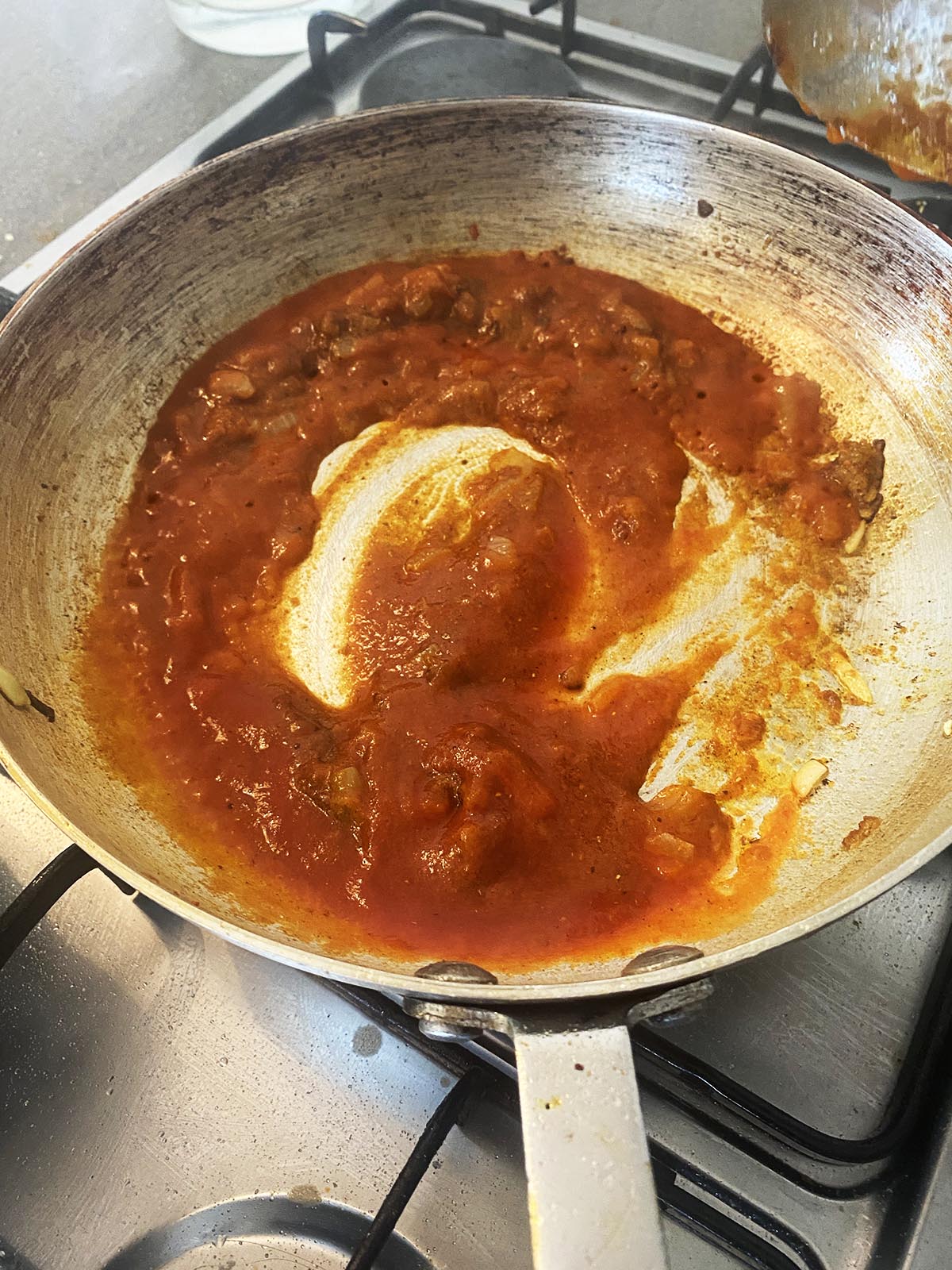 Adding tomato puree (pasatta) to the pan.