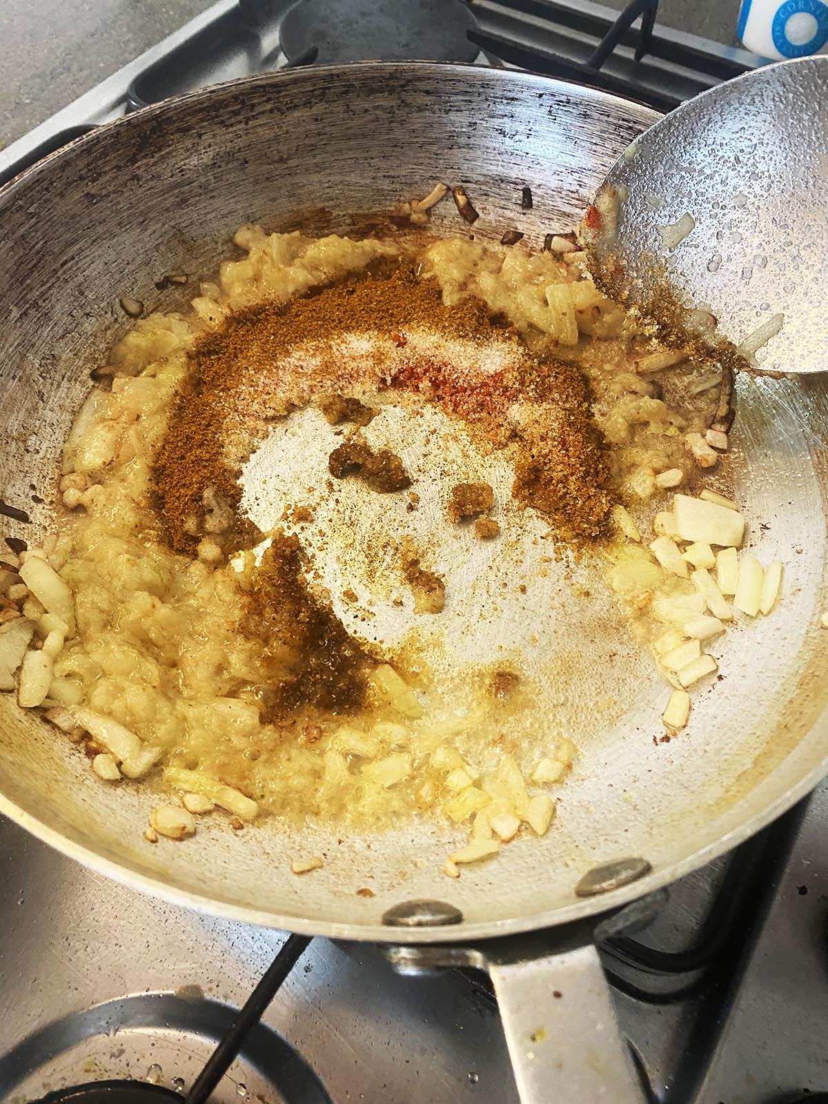 Adding spices to the onions, garlic and ginger in the pan