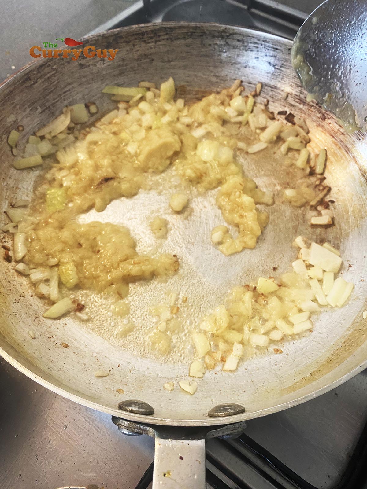Adding garlic and ginger paste to the frying onions in the pan.