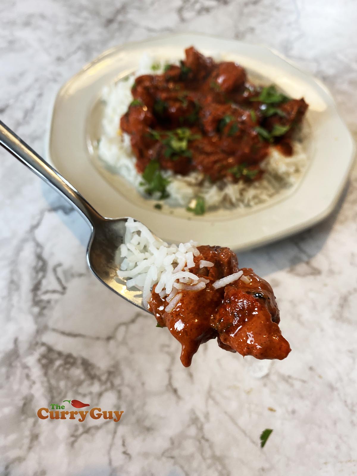 Authentic chicken tikka masala curry on a fork with rice.