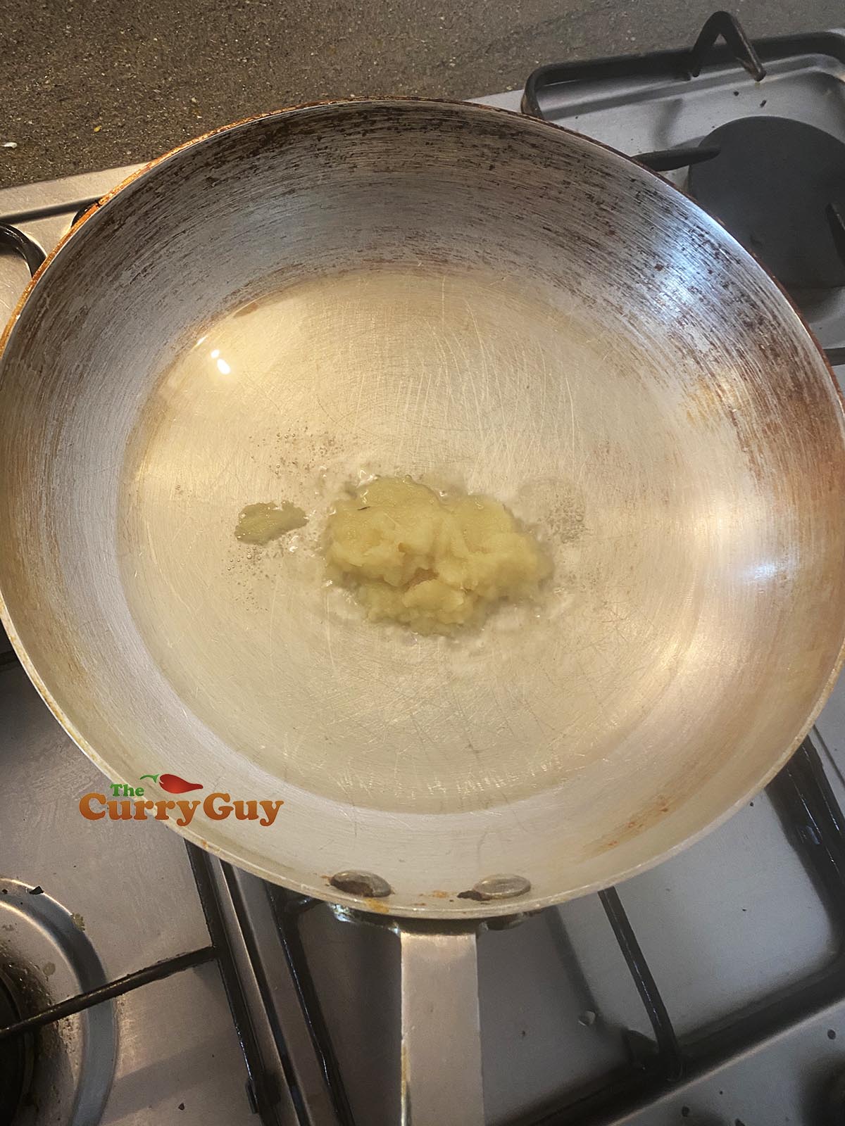 Frying garlic and ginger paste in oil in a hot pan.