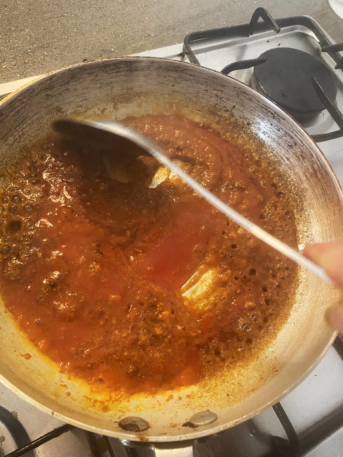 Adding tomato puree to the pan.