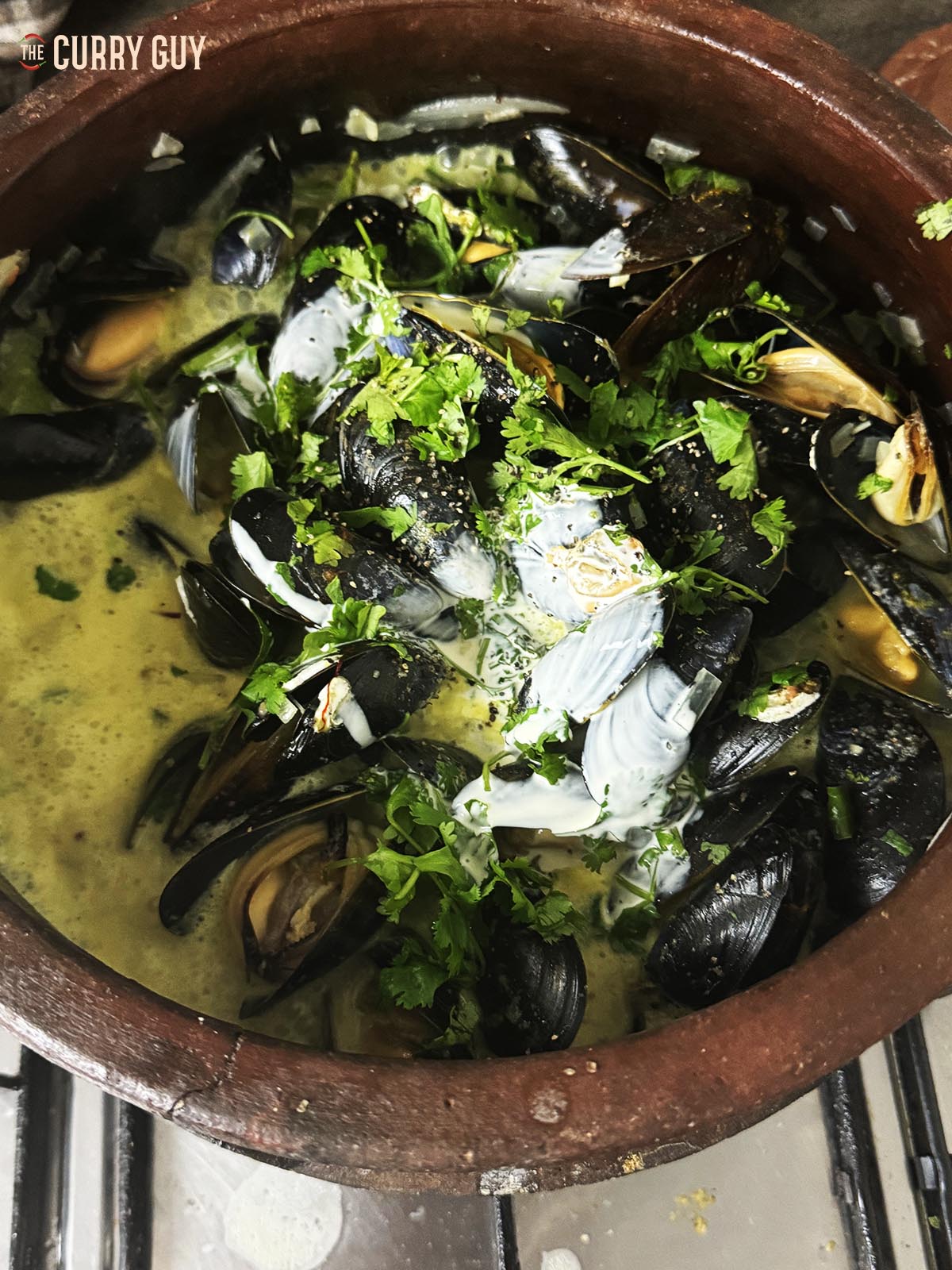 Adding the cream to the pot of mussels.