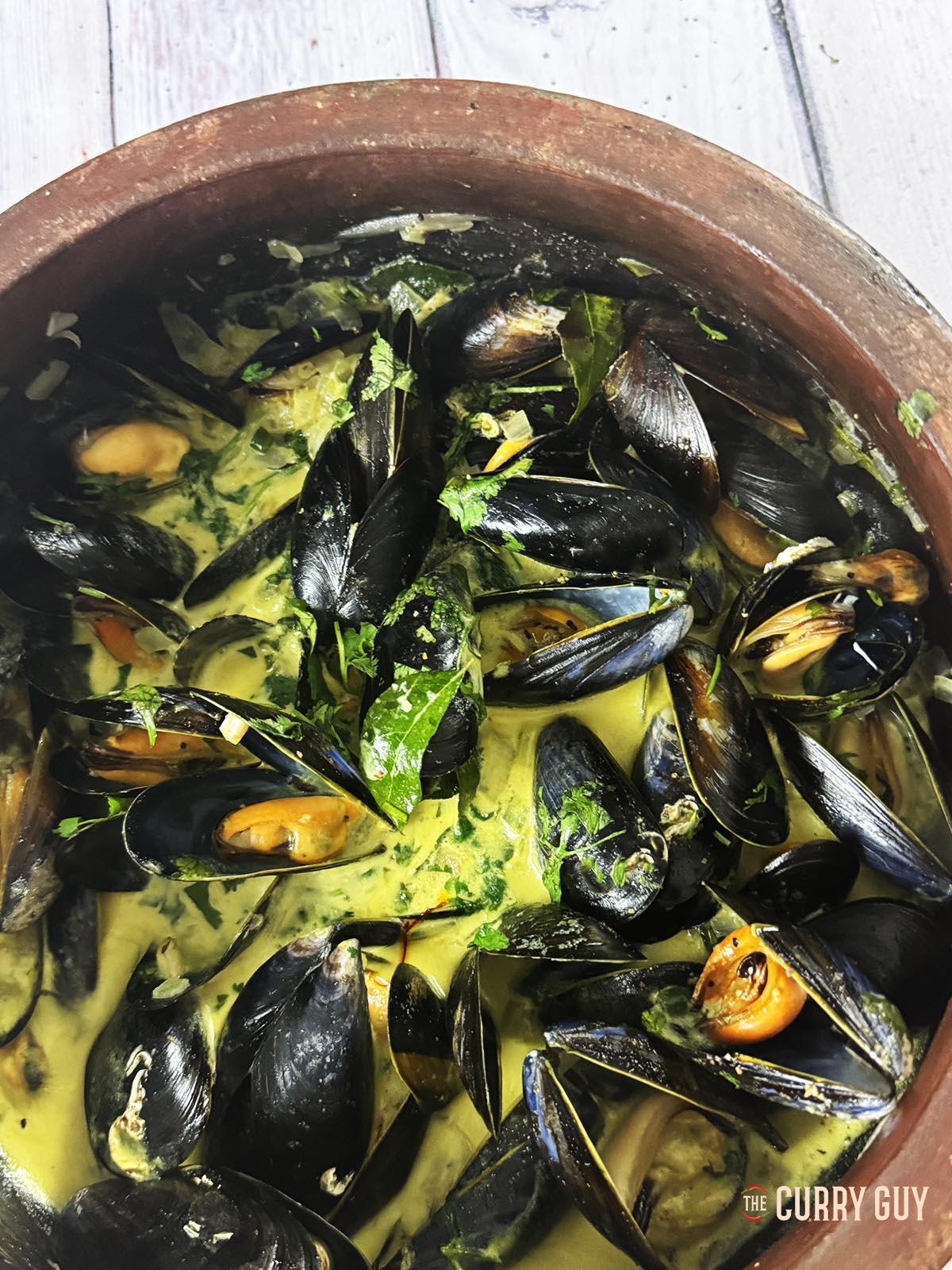 Coconut curry mussels ready to serve, garnished with chopped coriander.