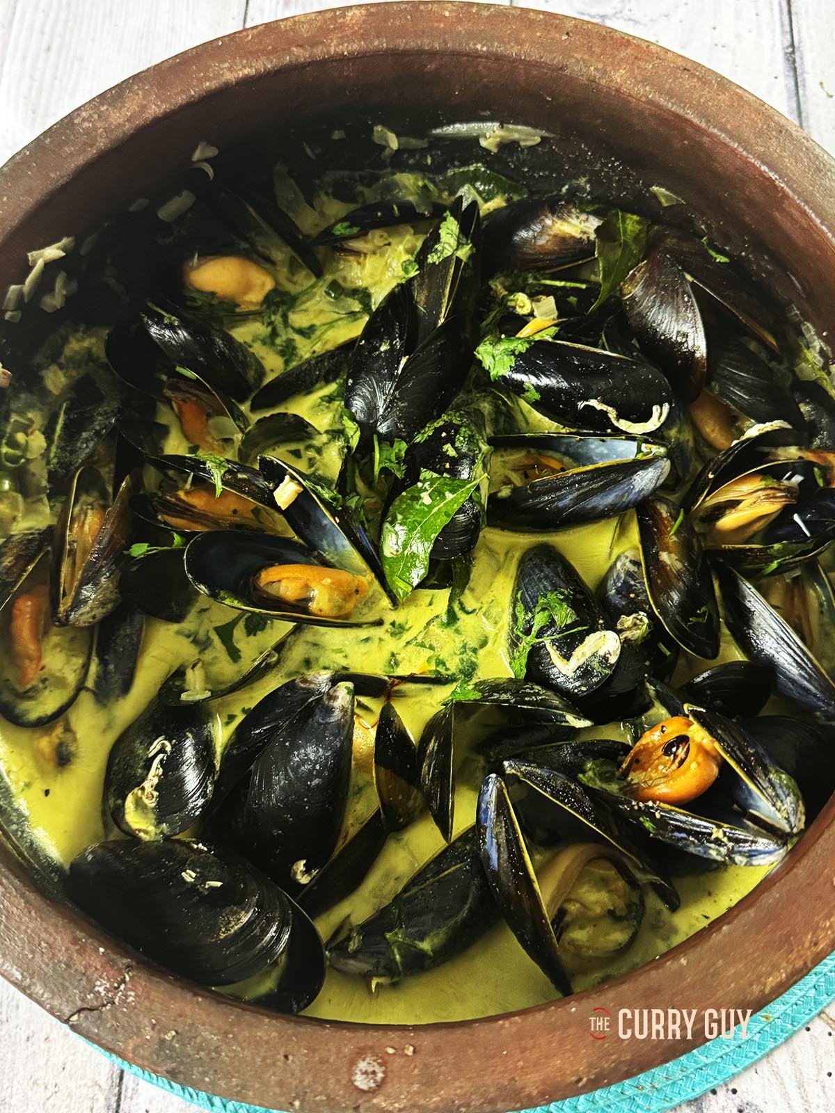 Coconut curry mussels in a clay pot just after cooking and ready to serve.