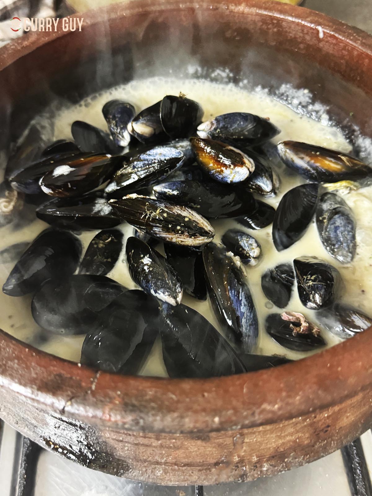 Adding the mussels to the simmering sauce.
