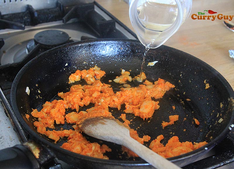 Adding wine to sauce.