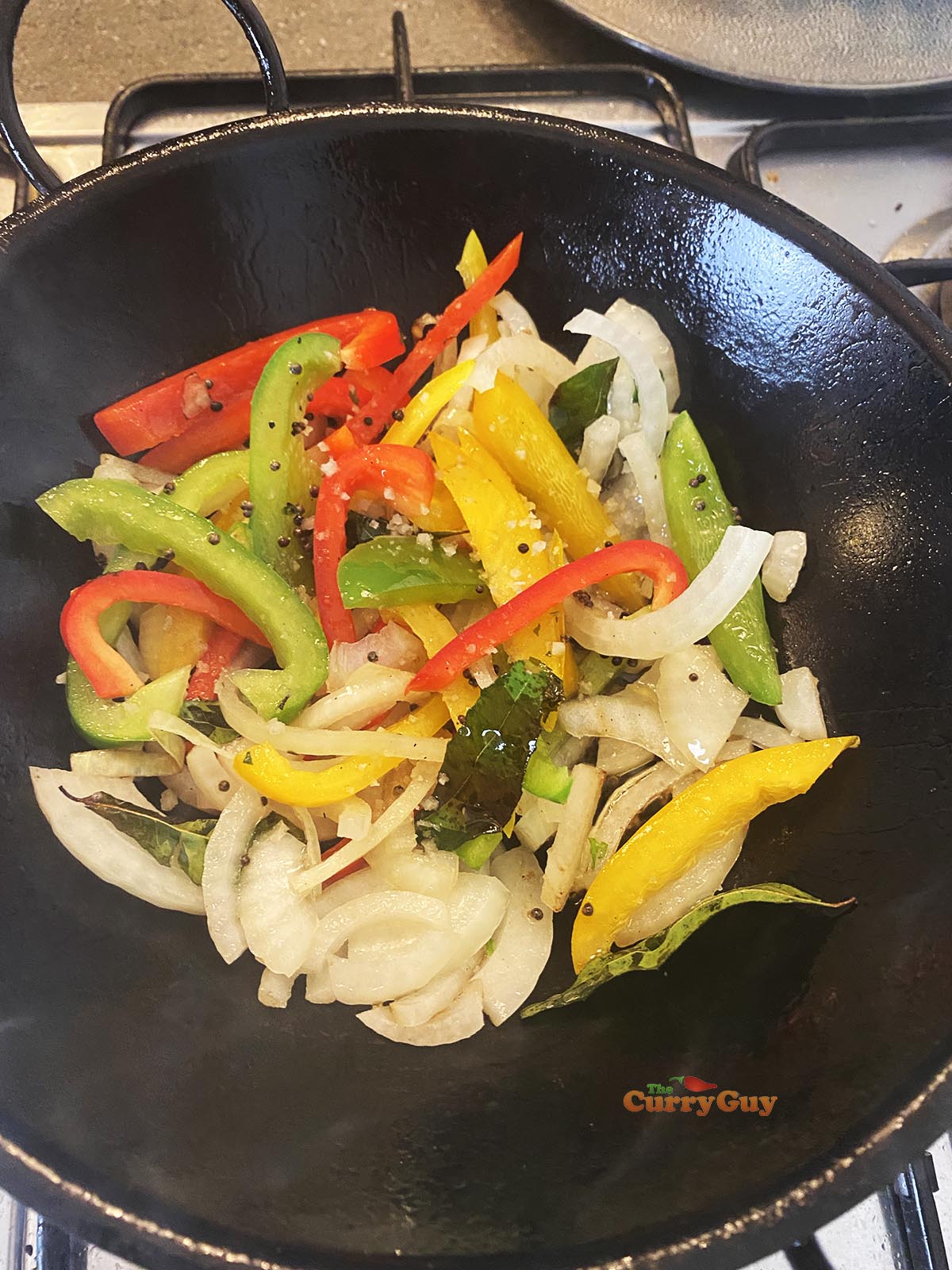Adding onions and peppers to pan
