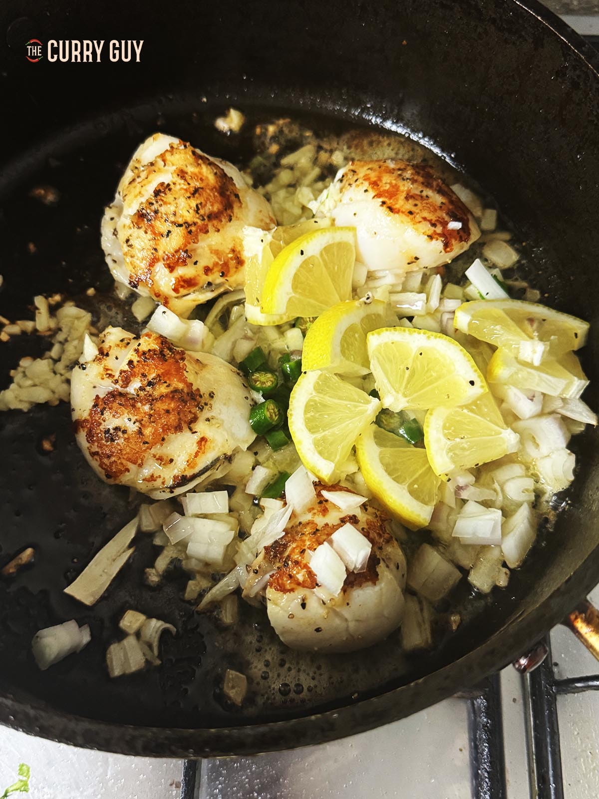 Adding lemon pieces to the pan with the other ingredients.