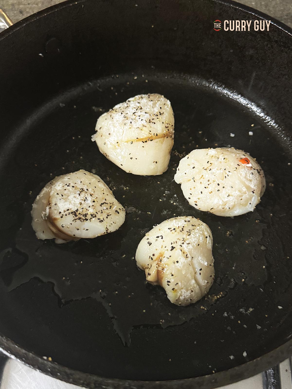 Placing the scallops in a hot pan to fry in oil. 