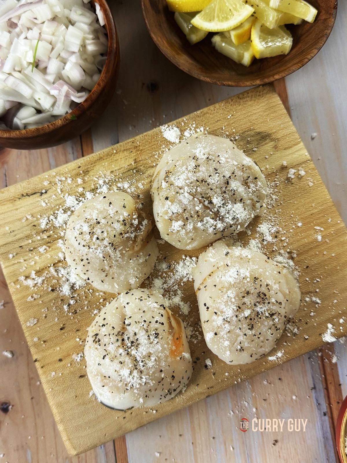 Seasoning the scallops with salt and pepper and dusting with flour to fry.