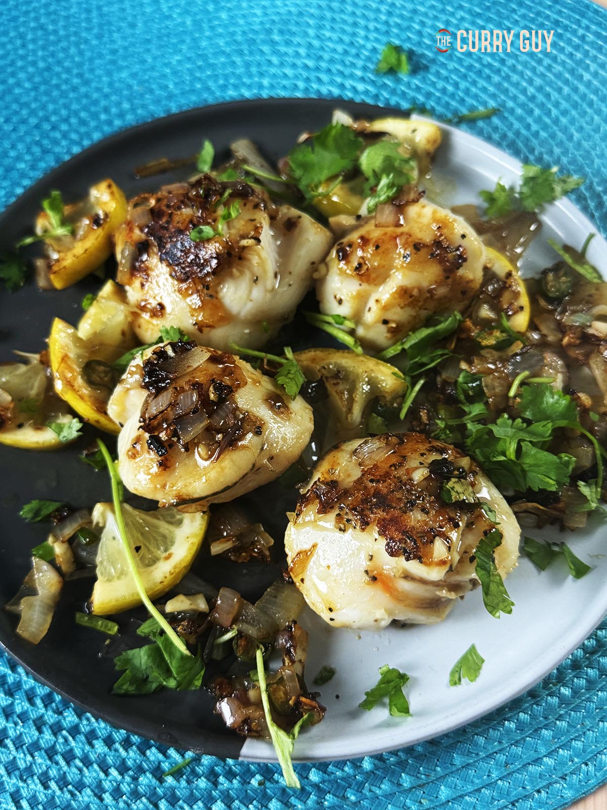 Pan seared scallops on a serving plate with the fried veggies and lemon and butter.