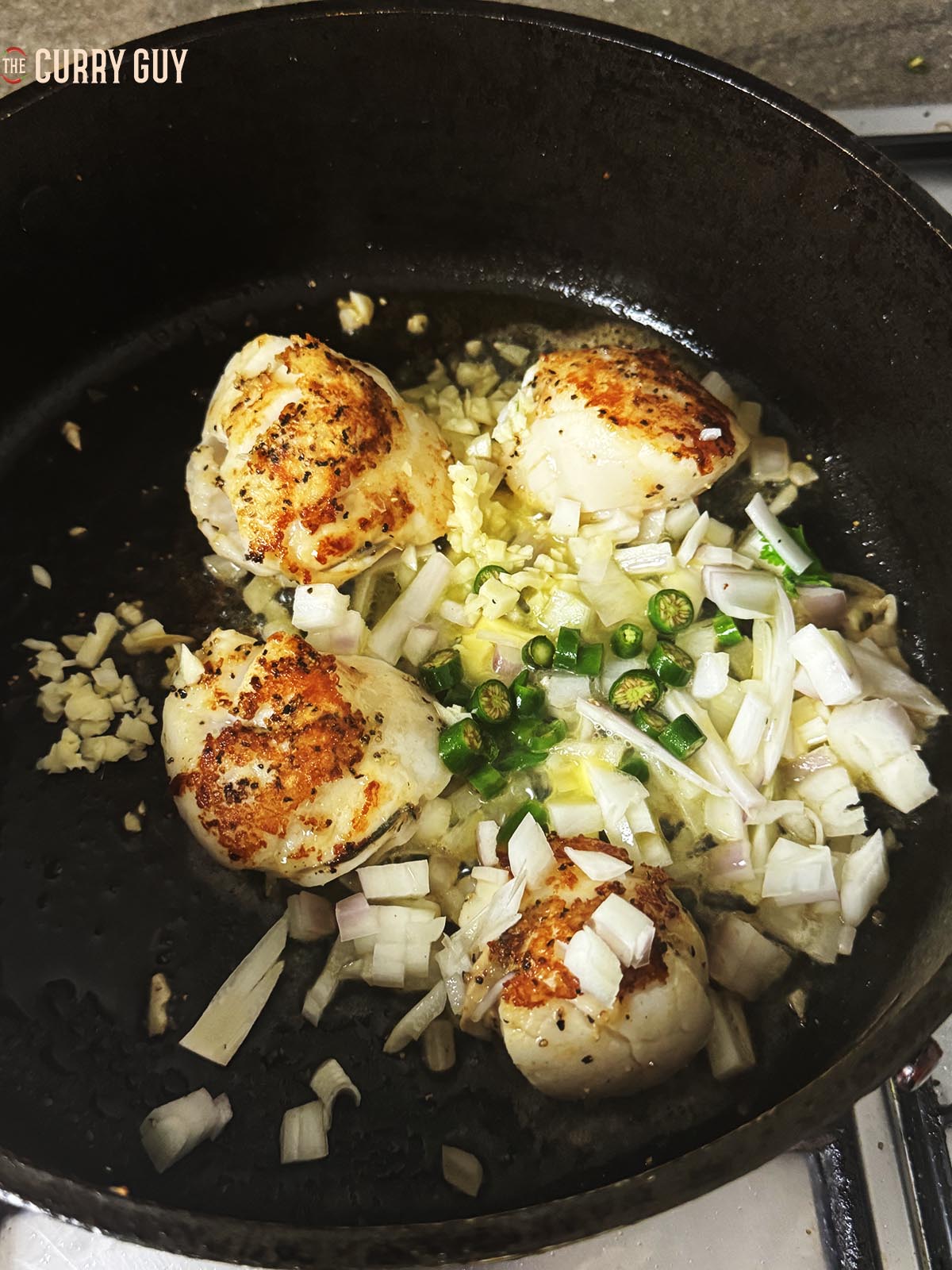 Adding the butter, garlic, shallots and chillies to the pan.