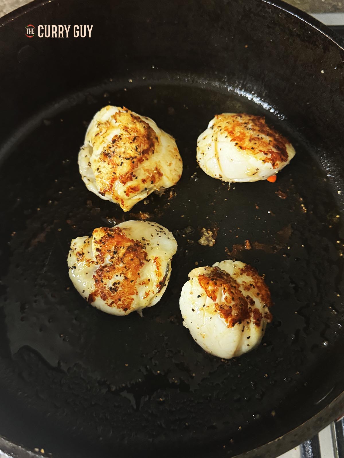 Flipping the scallops over to fry the other side.