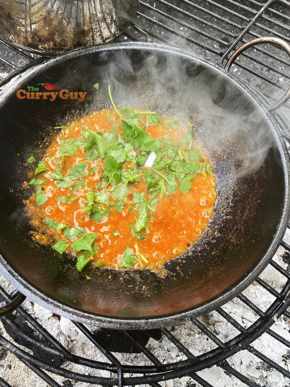 Adding coriander to balti bowl.
