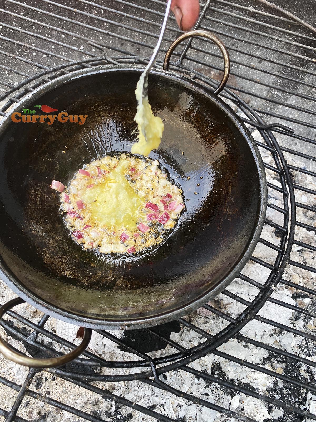 Adding garlic and ginger paste to balti pan