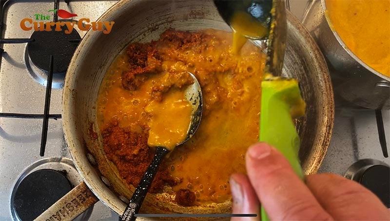 Stirring base sauce into the tikka masala mix.
