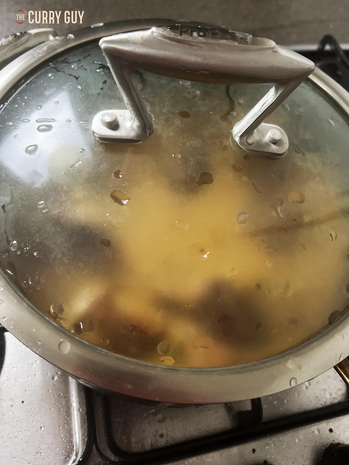 Covering the pan to simmer the curry.