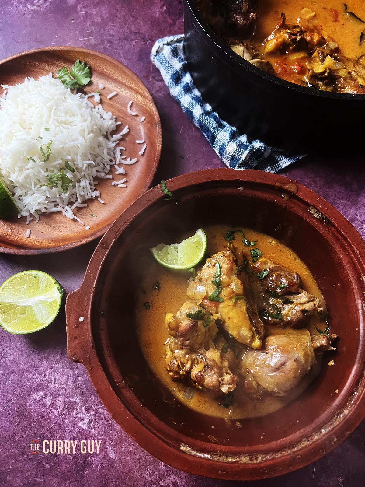 Pheasant curry in a serving bowl at the table next to rice.