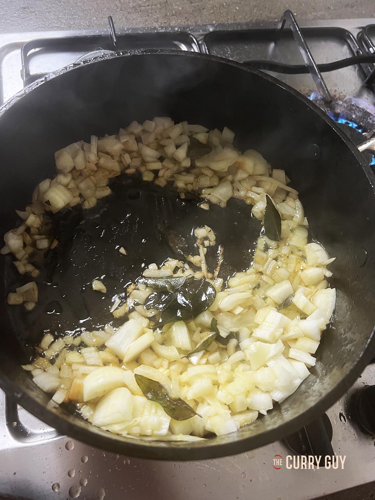 Frying the chopped onions with the curry leaves in a pan.