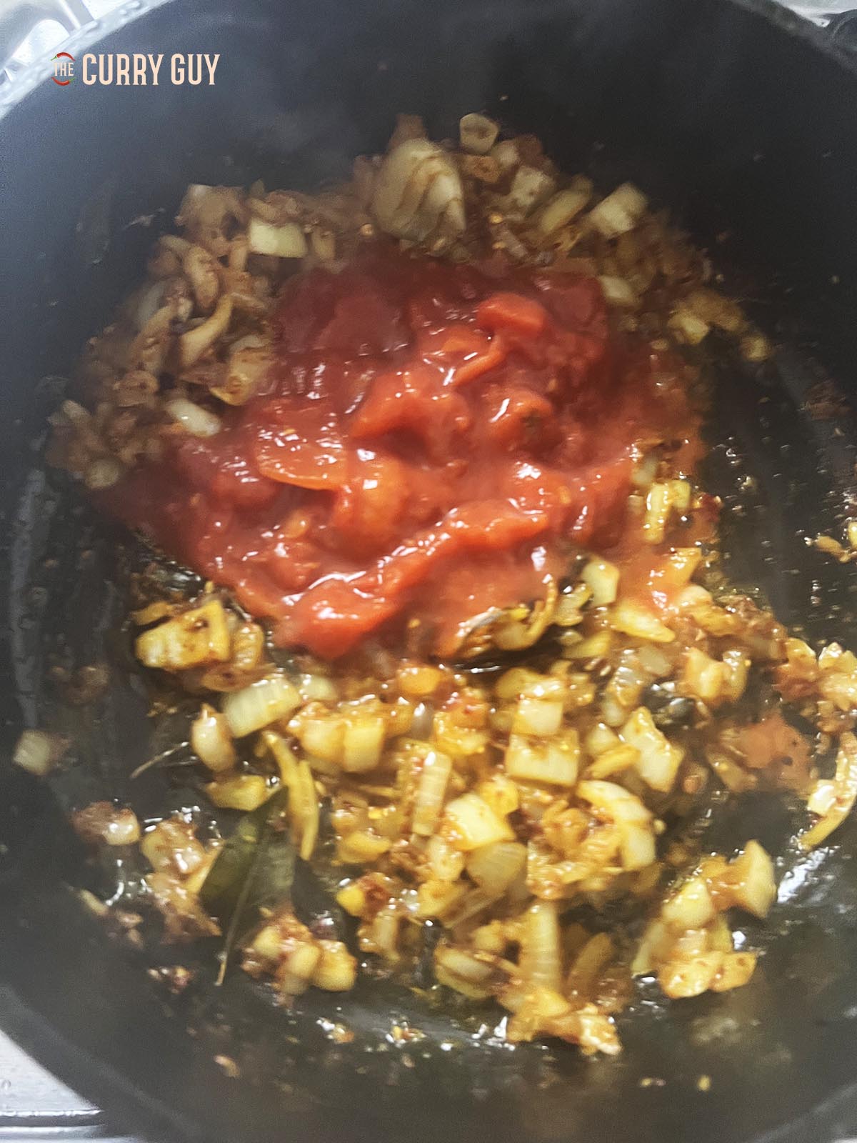 Adding chopped tomatoes to the fried onion mixture.
