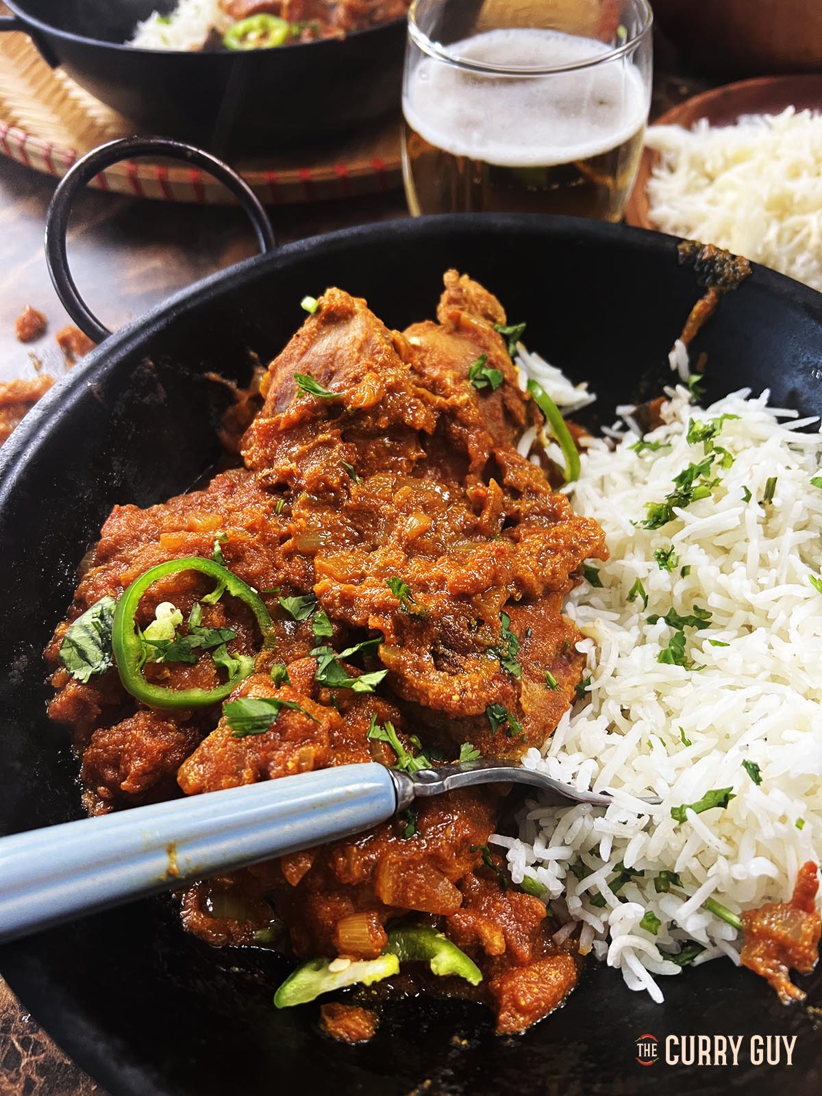 Spicy pheasant curry served at the table with rice and beer. 