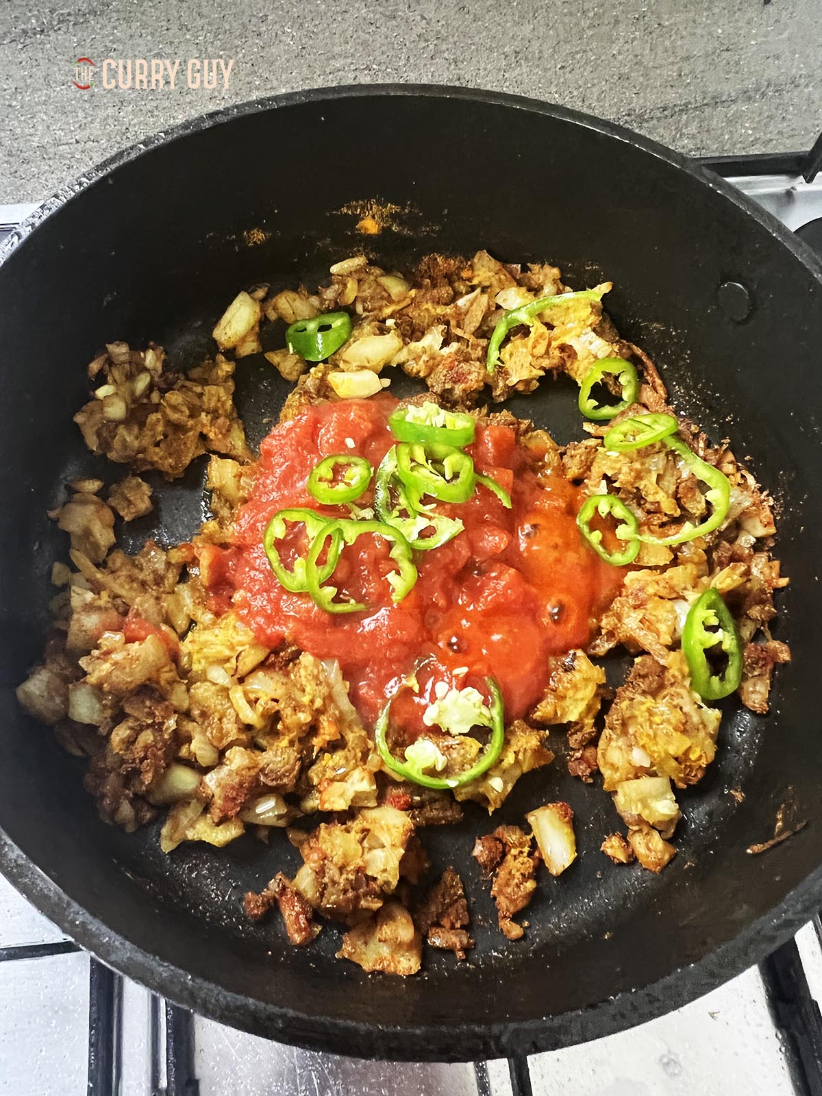 Stirring in the chopped tomatoes and sliced chillies.