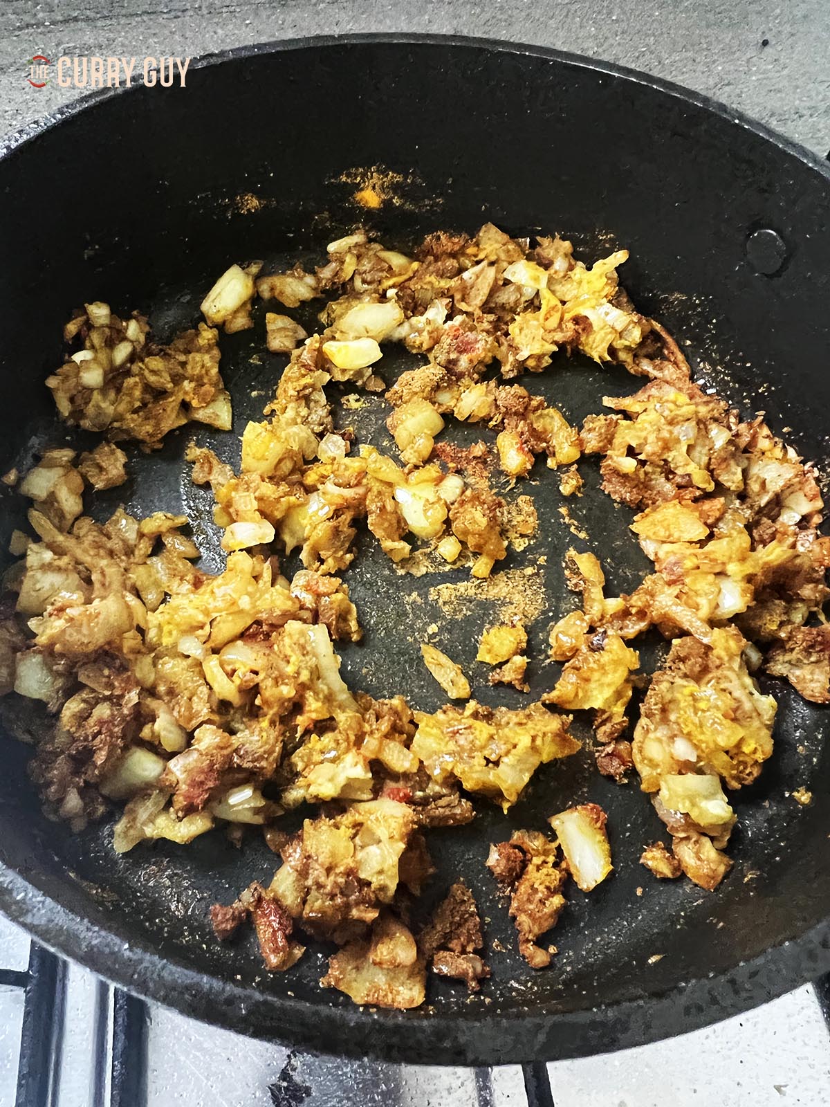 Adding the ground spices to the onions in the pan.
