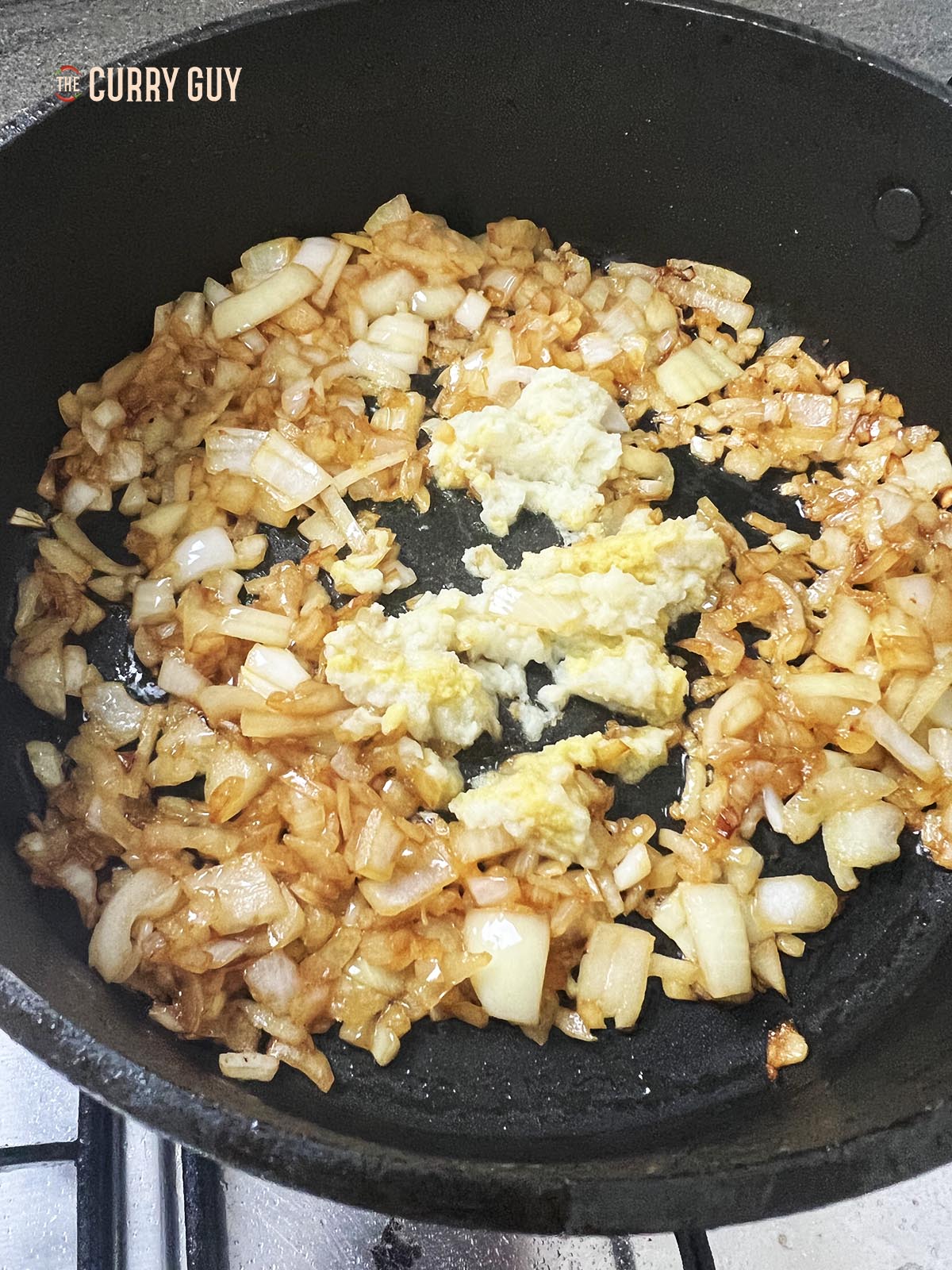 Adding the chopped onions and garlic and ginger paste to the pan.